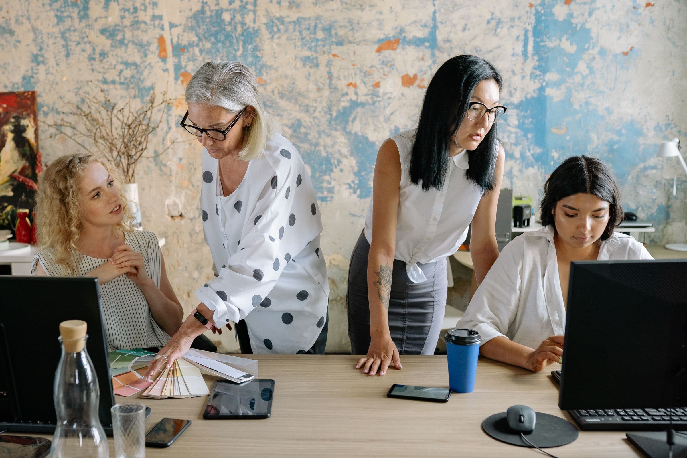 Four colleagues planning work together around a table in a bright office.